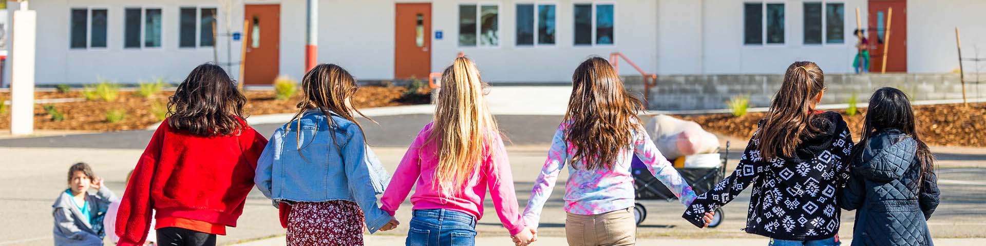 The back of students holding hands at Metteer School.